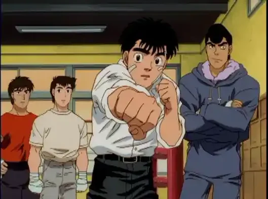 Ippo extends a fist in a boxing gym while Takamura and other boxers watch.