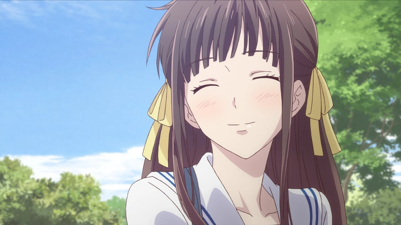 Tohru smiles with her eyes closed outside, yellow ribbons tied in her hair.