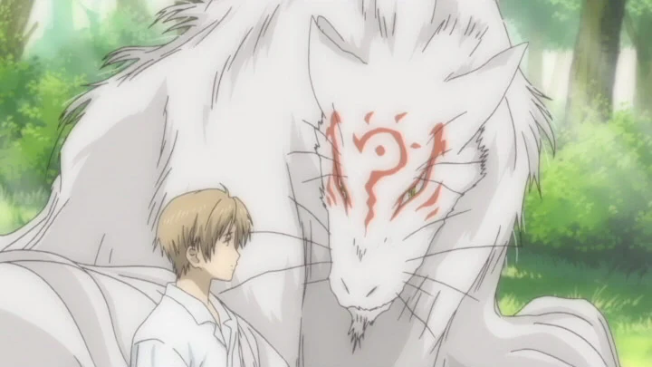 Natsume stands in a forest in front of a large white spirit with red markings.