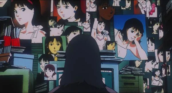 A seated figure faces a wall crowded with photographs and posters of Mima, seen from behind.