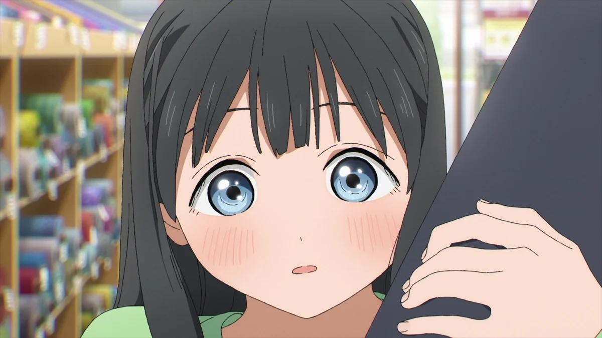 A dark-haired girl with blue eyes looks ahead while holding onto dark clothing.