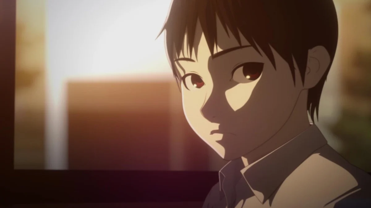 A dark-haired schoolboy turns his face toward the viewer in warm classroom light.