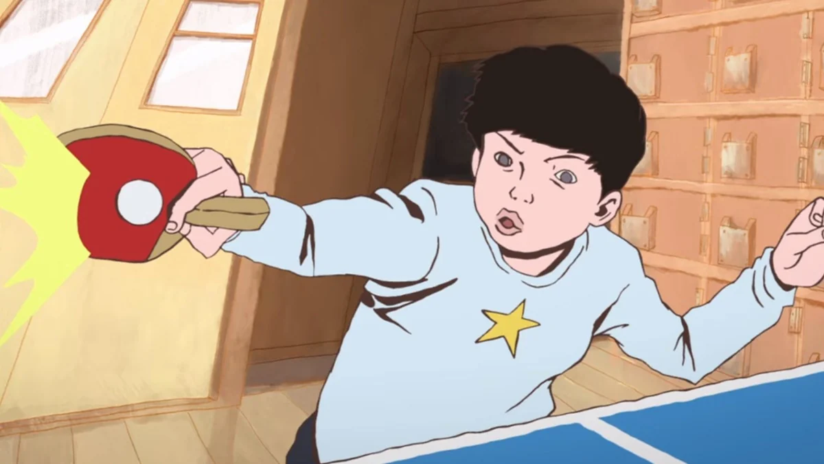 Peco reaches across the table with a red table-tennis bat.