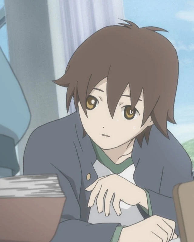 Taro crouches beside a desk among other school pupils.