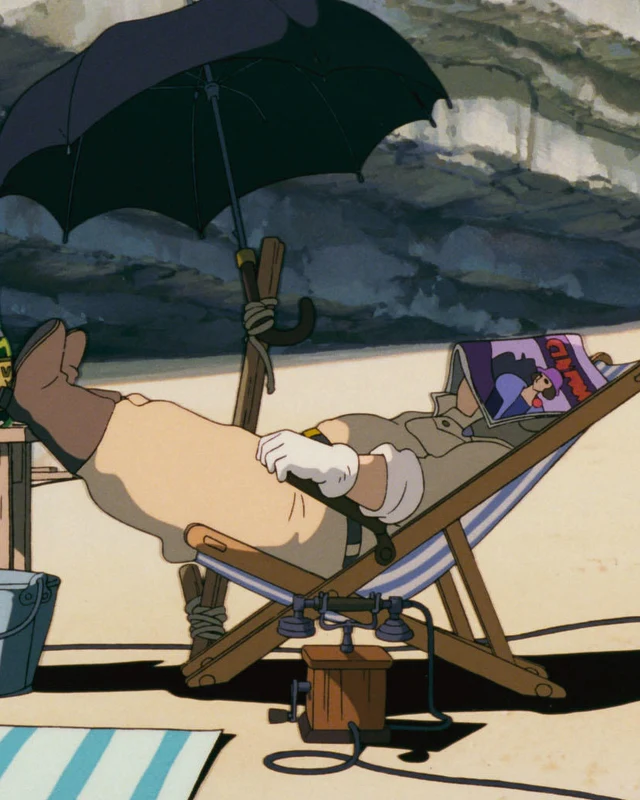 Porco reclines beneath a beach umbrella with a magazine covering his face.