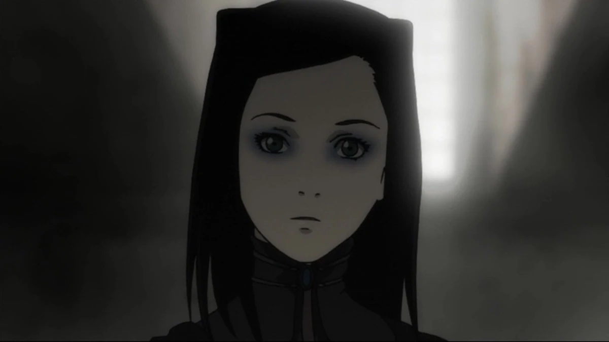 A dark-haired young woman looks forward in a dim interior.