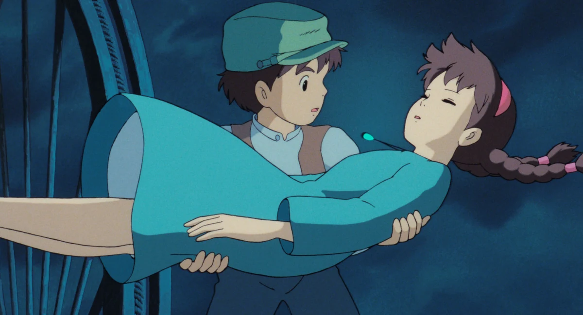 Pazu holds the unconscious Sheeta near a wooden structure against the dark sky.