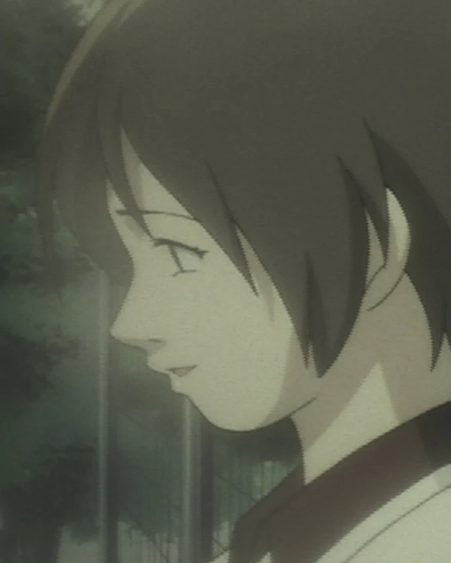 A short-haired school pupil looks down in profile in a shadowed setting.
