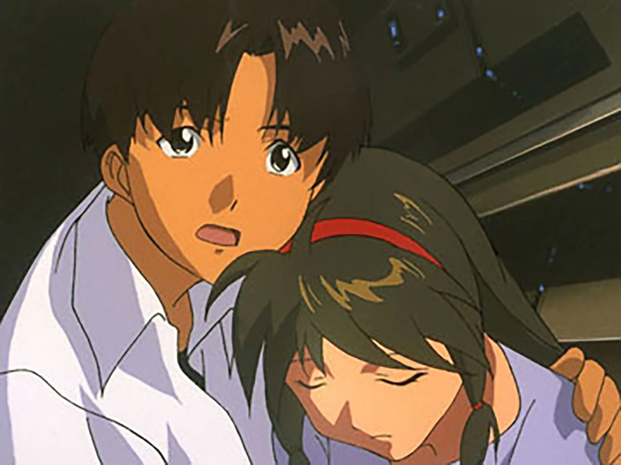 A boy supports a girl with closed eyes inside a dark corridor.