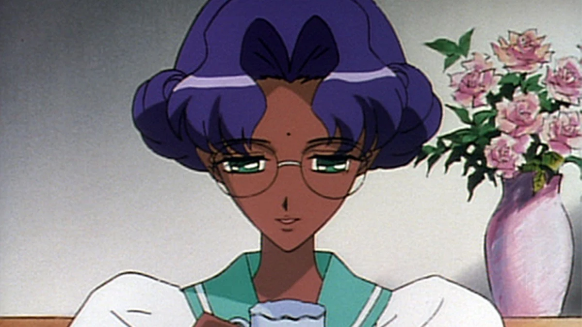 Anthy looks down through her glasses beside a vase of roses.