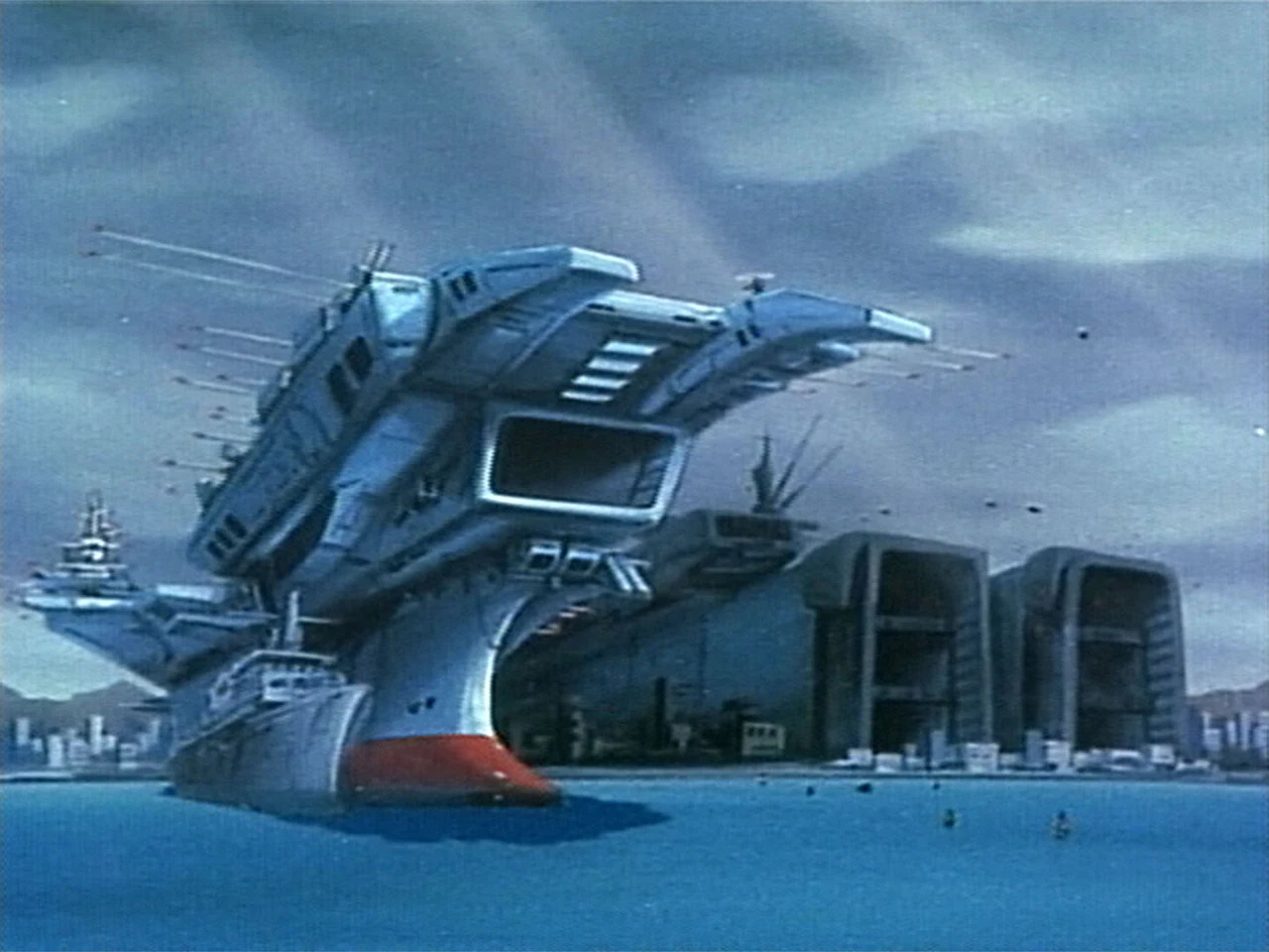 The Macross battleship rises above surrounding buildings.