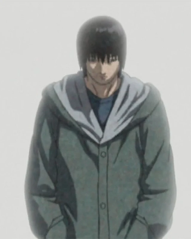 A dark-haired young man in a hooded coat stands against a pale background.