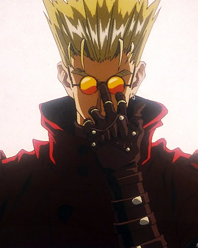 Vash raises a gloved hand below his tinted glasses and spiked hair.