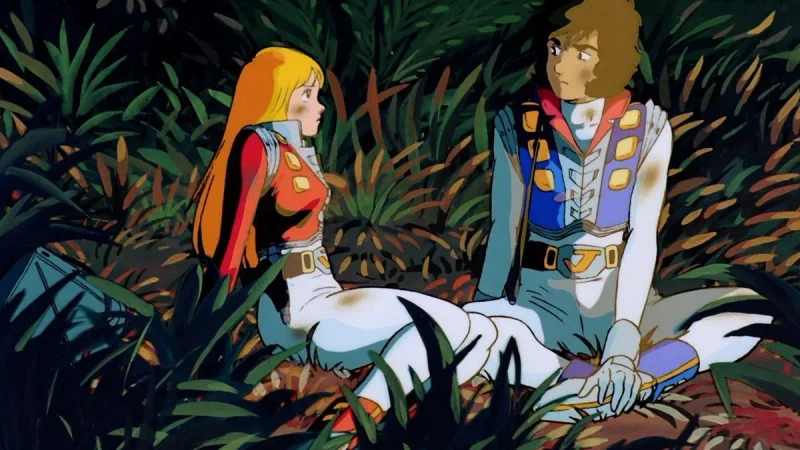 A brown-haired crew member in a blue-and-white uniform sits among dense leaves.