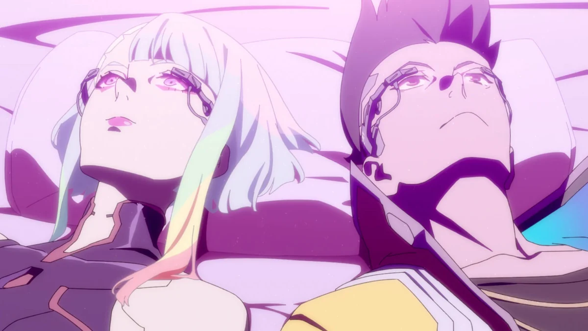 Lucy and David lie side by side wearing braindance headsets and looking upwards in pink light.