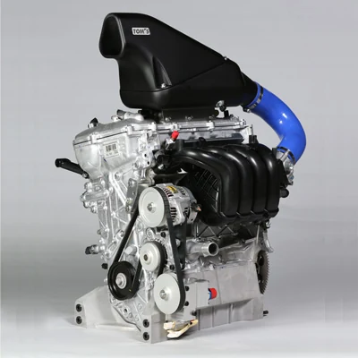 The TOM’S TZR42 engine, with its black intake assembly, blue hose and exposed metal casing.