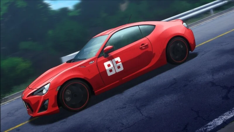 Kanata's red number 86 Toyota leans into a bend beside a roadside barrier.