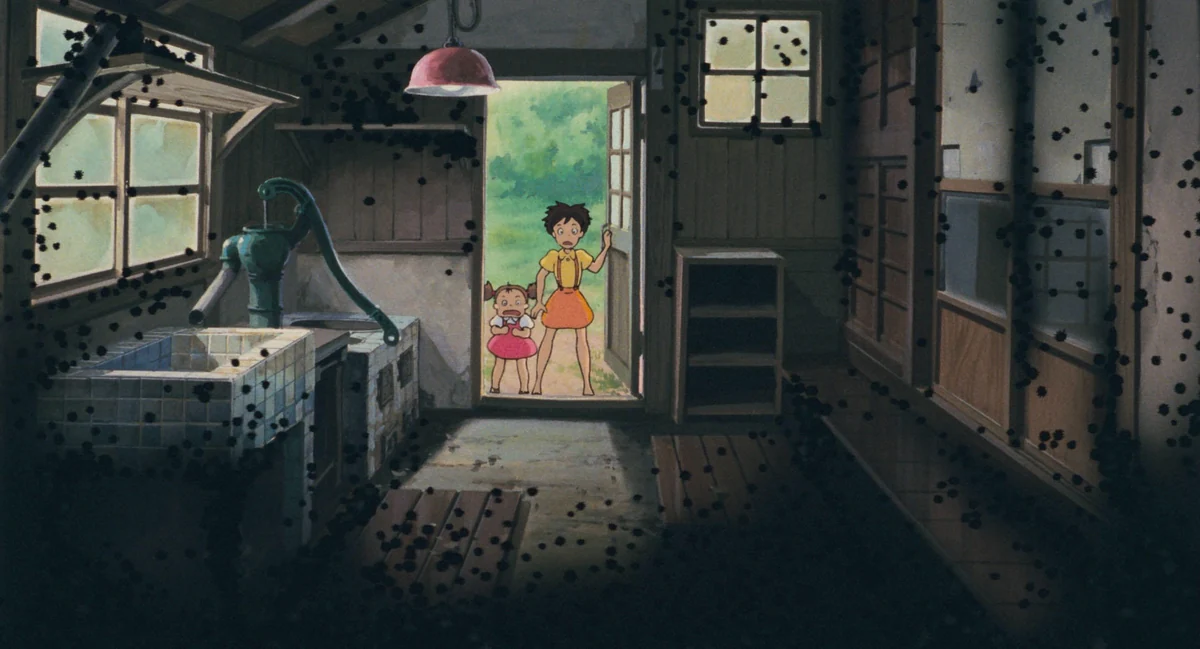 Satsuki and Mei peer into a dim room filled with tiny black soot creatures.